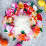 colorful easter wreath with crepe paper flowers and a fluffy bunny bottom in the center.
