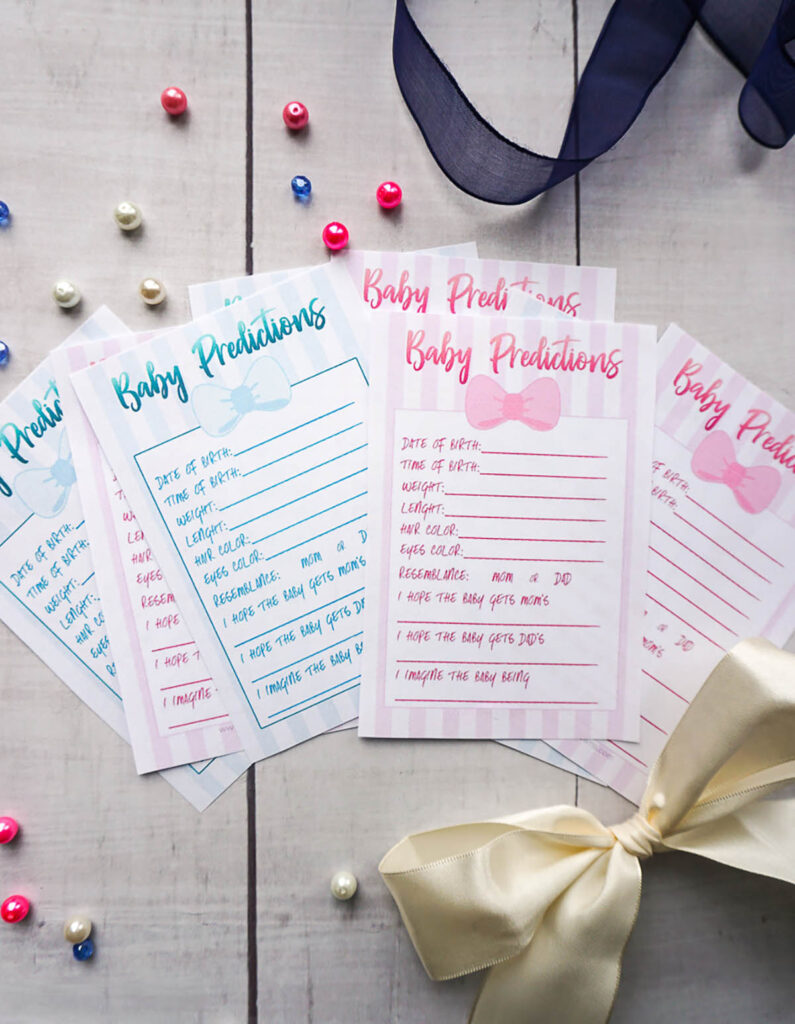 baby prediction cards laid out on a table next to a bow.