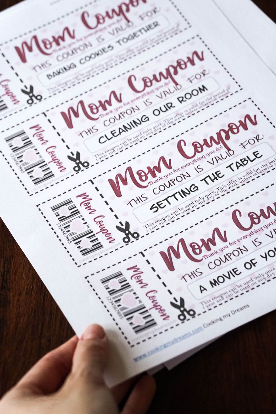 hand holding a printed paper with mom coupons.,