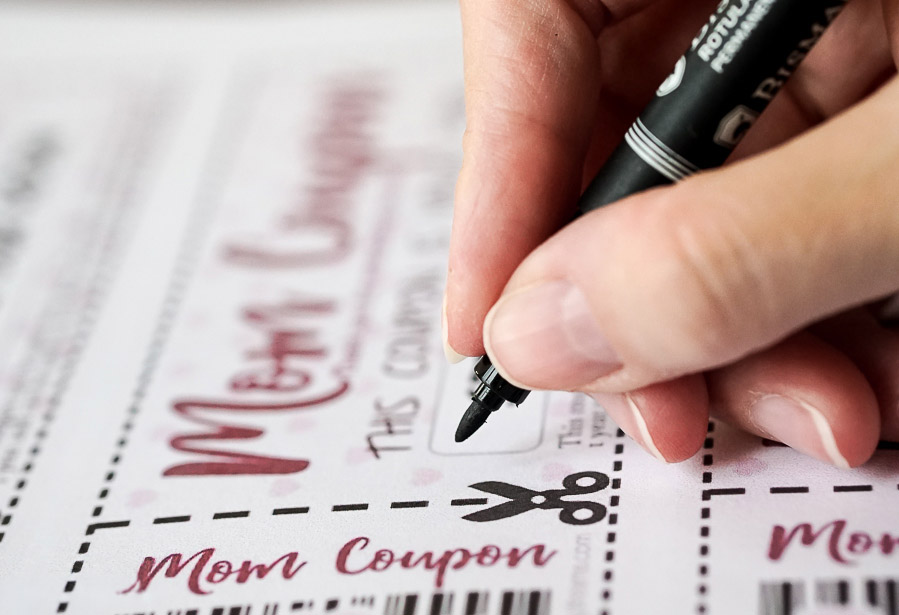 hand writing on a mom coupon with a pen.