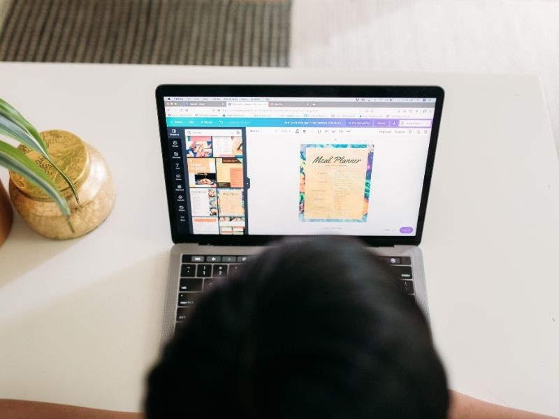 person sitting in front of a laptop showing a Canva page.