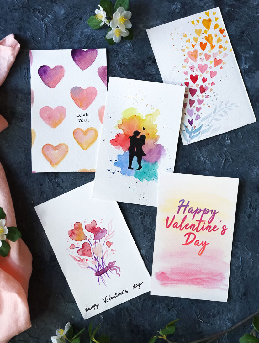 watercolor valentine's day cards on a dark blue table.